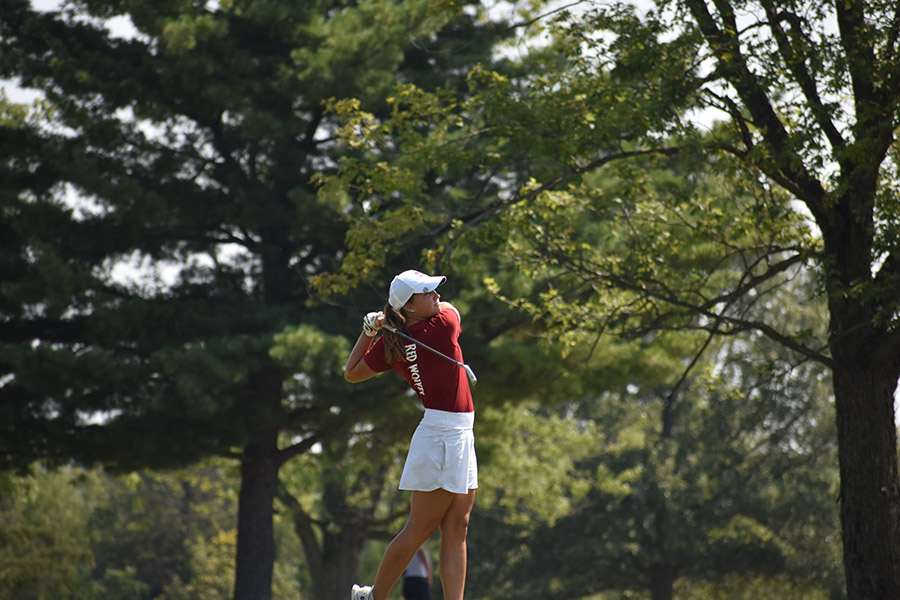 A female golfer takes a swing.